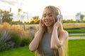 Young woman enjoys listening to music and singing while sitting in park Royalty Free Stock Photo