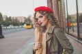 Cheerful young woman french model in red beret walking on city street