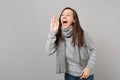 Cheerful young woman in gray sweater, scarf screaming with hand gesture on grey wall background. Healthy Royalty Free Stock Photo