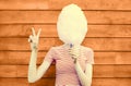 Cheerful young woman having fun covering her face with cotton candy in amusement park on wooden wall Royalty Free Stock Photo