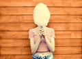 Cheerful young woman having fun covering her face with cotton candy in amusement park on wooden wall Royalty Free Stock Photo