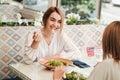 Cheerful Young Woman Having Lunch with Her Female Friend, Eating Salad with Shrimp in the Restaurant