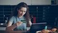 Cheerful young woman having online shopping using laptop computer and credit card while have breakfast in the kitchen at Royalty Free Stock Photo