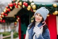 Cheerful young woman holding candy near the street Christmas deciration