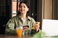 Cheerful Young Woman Holding Credit Card and Smartphone Making Online Shopping While Sitting at a Cafe Table with Laptop Royalty Free Stock Photo