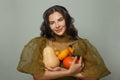 Cheerful young woman holding different orange pumpkins on white background. Thanksgiving or halloween portrait