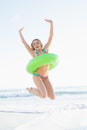 Cheerful young woman holding a rubber ring while jumping on a beach Royalty Free Stock Photo