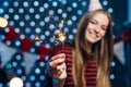 Cheerful young woman holding sparkler in hand. Christmas New Year