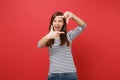 Cheerful young woman keeping mouth wide open, looking surprised, making hands photo frame gesture isolated on bright red Royalty Free Stock Photo