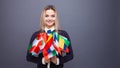 Cheerful young woman with a large set of flags of different countries of the world Royalty Free Stock Photo