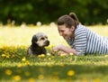 A cheerful, young woman lying on the grass with her pet.