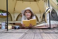 Cheerful young woman lying in her camping tent and reading a book. Travel, camping and vacation concept Royalty Free Stock Photo