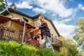 Cheerful young woman mows the grass using a lawn mower on the lawn in front of a country house