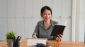 Cheerful woman office worker working with digital tablet and holding notebook. Royalty Free Stock Photo
