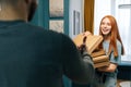 Cheerful young woman open box of hot pizza standing at entryway on apartment, smiling looking to delivery man. Royalty Free Stock Photo