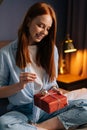 Cheerful young woman opening small gift box with present while having video call on laptop. Royalty Free Stock Photo