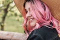 Cheerful young woman with positive smile with colored hair in straw vintage hat in jeans jacket is relaxing on nature. Beautiful Royalty Free Stock Photo