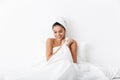 Cheerful young woman sitting in bed after shower