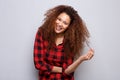 Cheerful young woman smiling against gray background with hand in curly hair Royalty Free Stock Photo