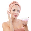 Cheerful young woman smiling, applying on face moisturizing skincare cream, lotion or mask for skin lifting and anti-aging, wears Royalty Free Stock Photo