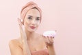 Cheerful young woman smiling, applying on face moisturizing skincare cream, lotion or mask for skin lifting and anti-aging, wears Royalty Free Stock Photo