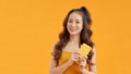 Cheerful young woman standing isolated over yellow background using mobile phone Royalty Free Stock Photo