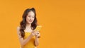 Cheerful young woman standing isolated over yellow background using mobile phone Royalty Free Stock Photo