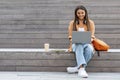 Cheerful young woman student working on project, using laptop outdoors Royalty Free Stock Photo