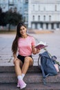 Cheerful young woman taking notes while sitting on steps otdoors Royalty Free Stock Photo