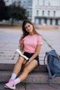 Cheerful young woman taking notes while sitting on steps otdoors Royalty Free Stock Photo
