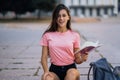 Cheerful young woman taking notes while sitting on steps otdoors Royalty Free Stock Photo