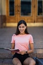 Cheerful young woman taking notes while sitting on steps otdoors Royalty Free Stock Photo