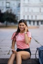 Cheerful young woman taking notes while sitting on steps otdoors Royalty Free Stock Photo