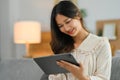 Cheerful young woman using digital tablet on couch, surfing the net or shopping online Royalty Free Stock Photo