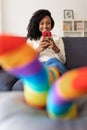 Cheerful young woman using mobile phone while relaxing on sofa at home Royalty Free Stock Photo