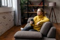 Cheerful young woman using mobile phone while sitting on a sofa at home. Royalty Free Stock Photo