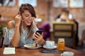 Cheerful young woman on a video call with friend while she is in cafe alone