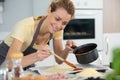 Cheerful young woman wearing apron preparing pastry