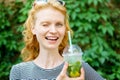 Cheerful young woman winking and holding cold mojito, closeup portrait Royalty Free Stock Photo