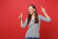 Cheerful young woman with wireless earphones dancing, pointing index fingers up, listening music isolated on bright red Royalty Free Stock Photo