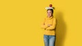 Cheerful young woman on yellow background in studio with a book and a red apple on her head. A smiling and happy girl. The concept Royalty Free Stock Photo