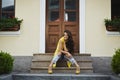Cheerful young woman in yellow casual outfit sitting on stairs outdoors. Happy model girl laughing and posing on a sunny Royalty Free Stock Photo