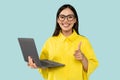 Cheerful young woman in yellow shirt holding laptop, pointing finger to camera and smiling, choosing you Royalty Free Stock Photo