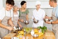 Positive young woman chef of cooking course teaching attendees how to mix sauce