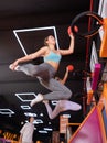 Young woman throwing ball in basket high jumping in trampoline arena