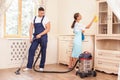 Cheerful young workers are cleaning the house with Royalty Free Stock Photo