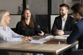 Cheerful younger and elder colleagues laughing at meeting table