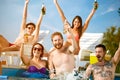 Cheerful youngsters group toasting with bottles of drink in piscine