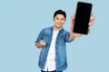 Cheerfull Asian man jumping and smiling in air with showing cellphone blank screen with empty space for mobile app on screen. Royalty Free Stock Photo