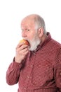 Cheerfull senior man eating the apple, isolated on white Royalty Free Stock Photo